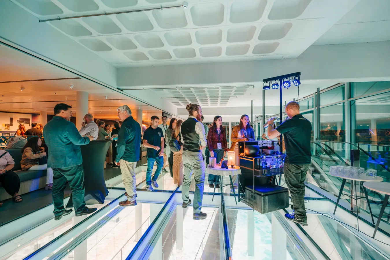 Asistentes conversan en un espacio acristalado de L’Aquàrium durante un encuentro corporativo en Barcelona