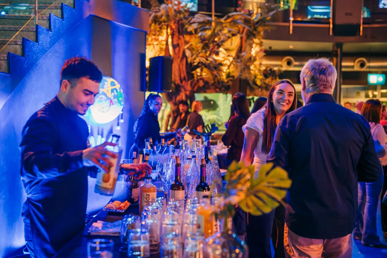 Un barman prepara bebidas para los asistentes de un cóctel corporativo en un espacio ambientado de L’Aquàrium.