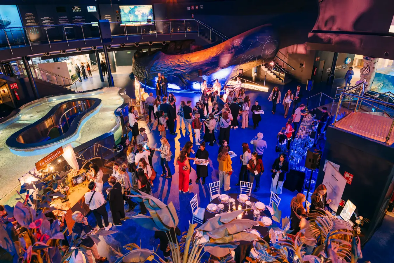 Invitados conversan alrededor de mesas antes de una cena celebrada en la Sala Planeta Aqua de L’Aquàrium.