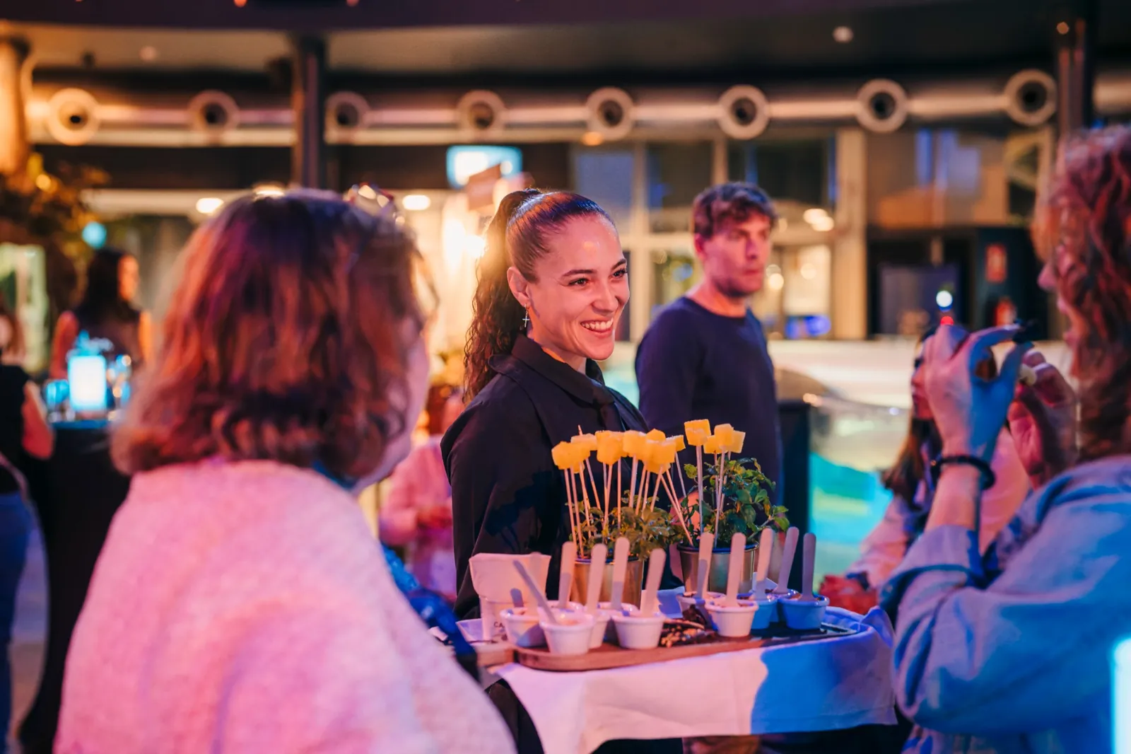 Una profesional de catering sirve aperitivos a los asistentes durante una celebración en L’Aquàrium.