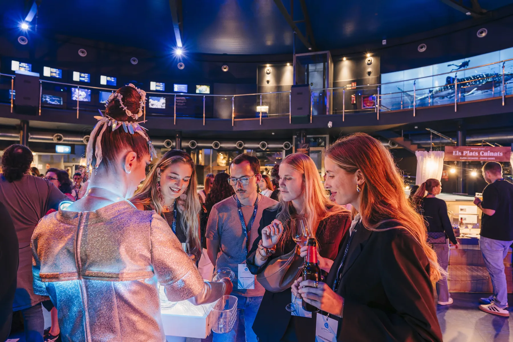 Varias invitadas comparten un brindis durante una experiencia nocturna con ambientación marina en L’Aquàrium.